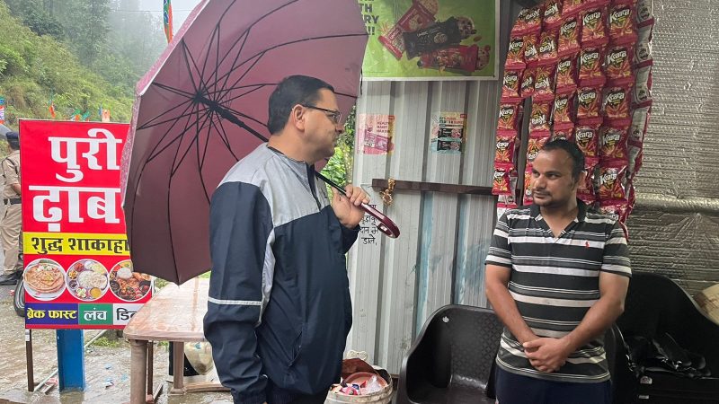 रिमझिम बारिश के बीच छाता लेकर आम लोगों से मिलने पहुंचे सीएम धामी